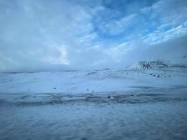 Icelandic winter landscape with snow covered hills and blue cloudy sky photo