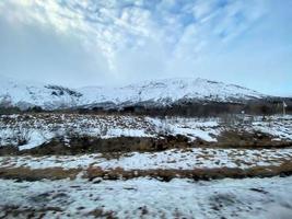 Icelandic winter landscape with snow covered hills and blue cloudy sky photo