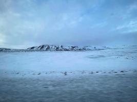 Icelandic winter landscape with snow covered hills and blue cloudy sky photo