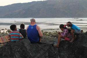 Lombok, Indonesia - August, 2014. tourists and local children playing together on the beach photo