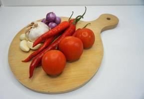 Garlic, Chili, red onion and tomatoes on a wooden coaster, High Angle shot. photo