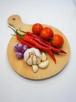 Garlic, Chili, red onion and tomatoes on a wooden coaster, High Angle shot. photo