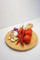 Garlic, Chili, red onion and tomatoes on a wooden coaster, High Angle shot. photo