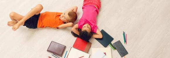 Happy children are lying on the floor. Top view photo