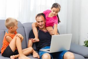 sonriendo padre y enfocado hija utilizando ordenador portátil a hogar foto