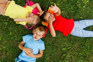 Happy children lying on grass in park photo