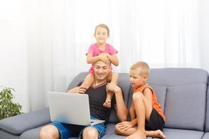 niños y su padre utilizando un computadora portátil, en línea aprendizaje a hogar foto