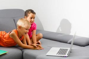 Lovely children watching a movie on their laptop at home photo