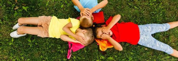 Happy children lying on grass in park photo