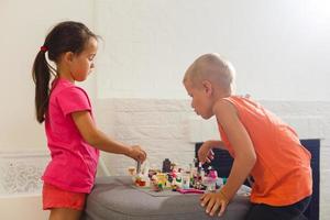 los niños juegan con un diseñador de juguetes en el suelo de la habitación de los niños. dos niños jugando con bloques de colores. juegos educativos de jardín de infantes. foto