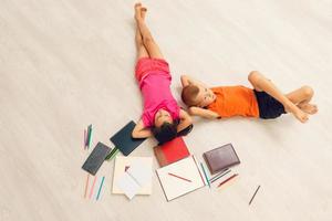 Happy children are lying on the floor. Top view photo