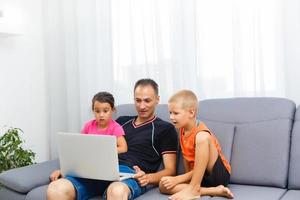 Man and two children sitting in living room smiling photo