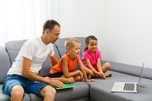 Man and two children sitting in living room smiling photo