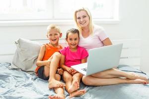 Happy mother and kids using digital laptop at home photo