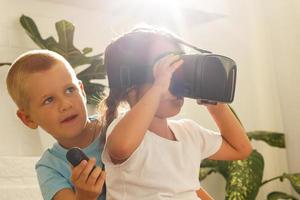 Pretty cute girl in virtual reality glasses device playing the game having fun sitting on in the living room at home. family activity concept. photo