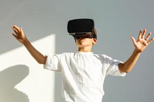 Amazed little boy looking in a VR goggles and gesturing with his hands isolated on white background photo