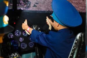 un feliz, jardín de infancia chico cargando en un de gran tamaño aerolínea piloto uniforme foto