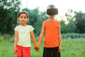 Adorable little kids in virtual reality headsets playing together in park photo