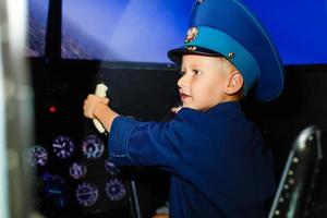 A happy, kindergarten boy toting in an oversized airline pilot uniform photo