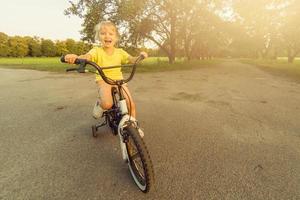 Little girl learns to keep balance while riding a bicycle photo