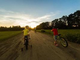 Three child riding a bicycle. The kids in a helmet riding a bike in the park. Beautiful kids. photo