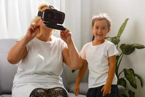 A young girl explains to an elderly woman how to use virtual reality glasses. The older generation and new technologies. photo