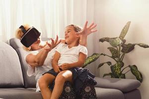 abuela y nieta. contento antiguo mujer jugando virtual realidad con pequeño niña a hogar. realidad virtual, aumentado realidad vídeo y tecnología. foto