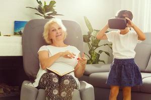 girl, grandmother with VR goggles at home. photo