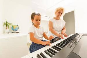 grandmother and granddaughter play the piano photo