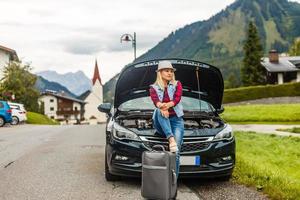Woman with car near countryside road through mountain Alps photo