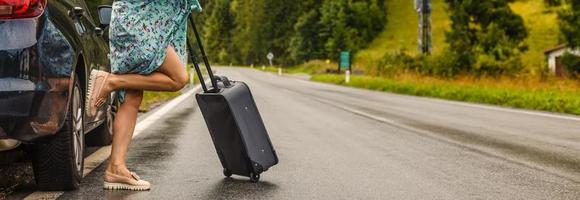 cropped image of woman carrying wheeled bag while her friends waiting near travel bus at urban street photo