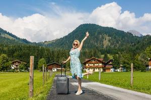 woman in the summer goes on vacation, on vacation with an suitcase on the background of nature and mountains. The concept of travel, weekend in a beautiful place in the mountains