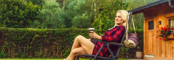 Outdoors lifestyle portrait of travelling girl holding a cup of coffee. Enjoying amazing view on the bay. Wearing checkered shirt. Early morning. Travelling and tourism concept. Feeling freedom photo
