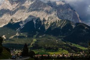 Idyllic landscape in the Alps with fresh green meadows, blooming flowers, typical farmhouses and snowcapped mountain tops in the background, Nationalpark Berchtesgadener Land, Bavaria, Germany photo