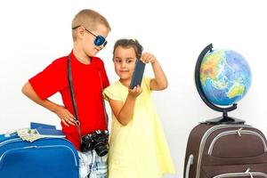 The young traveler brother and sister with a suitcase. Isolated over white background photo