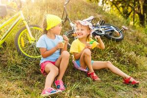 two little girls rest bike resting in a park near their bike photo