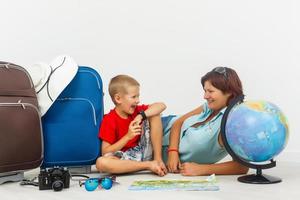 Travelling with kids. Happy mother with her child packing clothes for their holiday photo