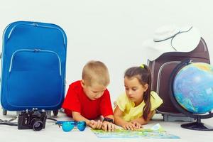 Children travel abroad - boy and girl choose a country to visit on a map and on a globe. Isolated, white background photo