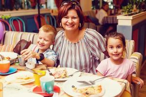 Family mother boy girl eating in cafe or restaurant, summertime photo