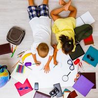 Children boy and girl playing together drawing lying on the floor, top view photo