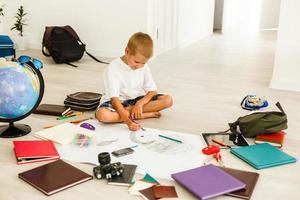 School boy drawing while sitting on a floor photo