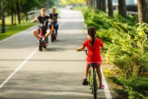 niños aprendiendo a conducir una bicicleta en un camino afuera. niñas pequeñas montando en bicicleta en la carretera de asfalto en la ciudad foto