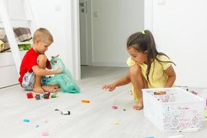 niños chico y niña hermanos jugando a hogar con educativo juguete bloques foto