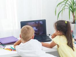 covid-19 coronavirus y aprendizaje desde hogar, hogar colegio niño concepto. pequeño niños estudiar en línea aprendizaje desde hogar con ordenador portátil. cuarentena y social distanciamiento concepto. foto