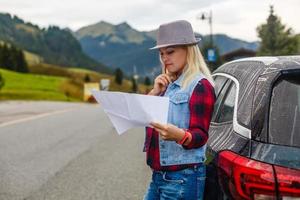 Young woman traveler with a map on the background of the Alps. Active leisure, lifestyle sports, hiking in the mountains. Travelling in Europe. photo