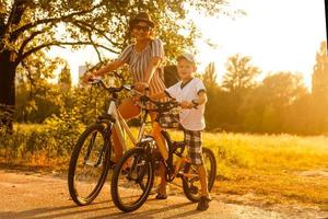 contento familia es montando bicicletas al aire libre y sonriente. mamá en un bicicleta y hijo en un bicicleta de equilibrio foto