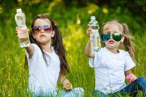 two little girls holding bottles with water photo