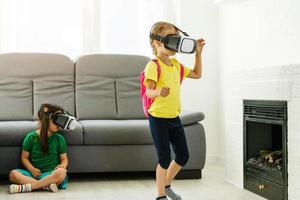 Lifestyle shot of an amazed two little kids using a virtual reality goggles with mouth open shocked seated in the living room at home. family activity concept. photo