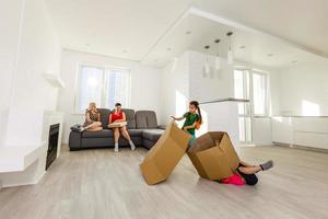 Cute small kids carrying boxes playing together on moving day concept, active happy girls chasing each other in living room, excited children having fun helping parents pack unpack in new home photo