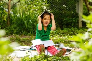 Lille girl portrait with books in garden during self education at home. Distant remote self learning. Modern school family study. photo